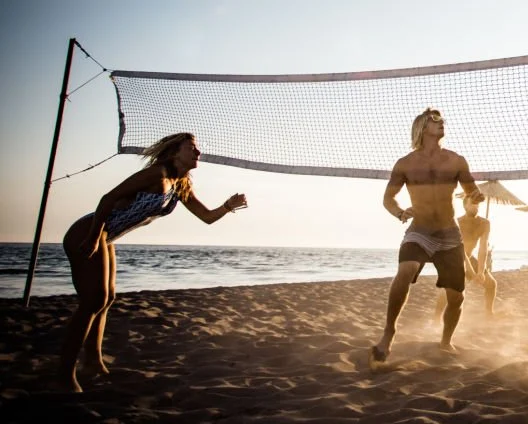 Giovani che giocano a pallavolo in spiaggia